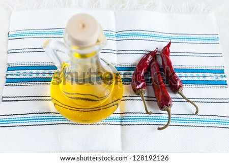 Bottle vegetable oil and three hot peppers on handmade fabric. Food ingredients. Top view