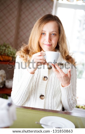Smiling young woman with a cup of coffee in hand. Coffee-break