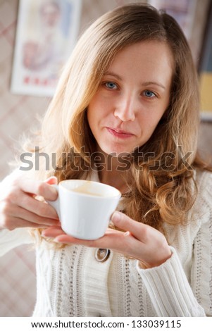 Positive young woman with a cup of coffee in hands. Coffee-break