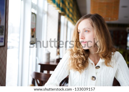 Portrait of a beautiful young sad woman.  Girl lonely in cafe