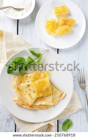 Pancakes with honey on a white plate, sweet food. Top view