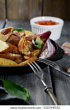 Roasted Potatoes with sauce and spices in a pan. Wooden background
