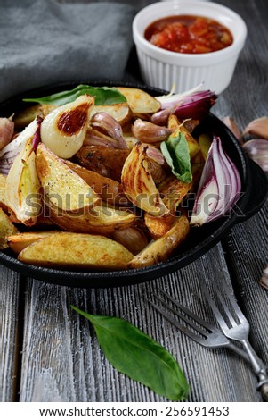 Crispy oven-baked potato slices in a pan. Wooden background
