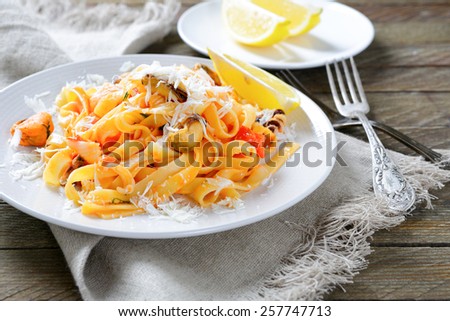 Pasta with seafood on a white plate on wooden background