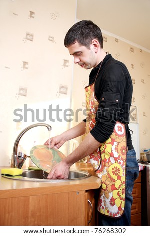 Young man washing dishes in the kitchen. Home work