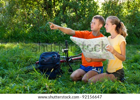Young couple tourist read the map and show the direction against a background of green nature