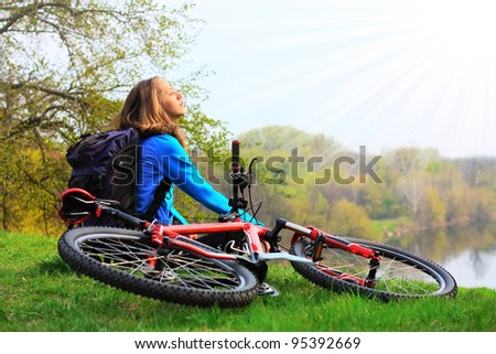 Woman cyclist relaxing, face to the sun\'s rays. At halt