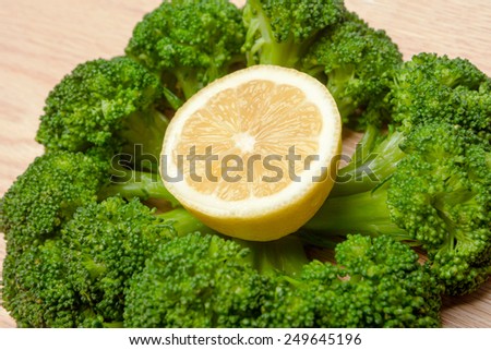 Broccoli round shaped with a slice of lemon in the middle  on a plank of wood