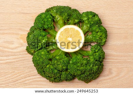 Broccoli round shaped with a slice of lemon in the middle  on a plank of wood