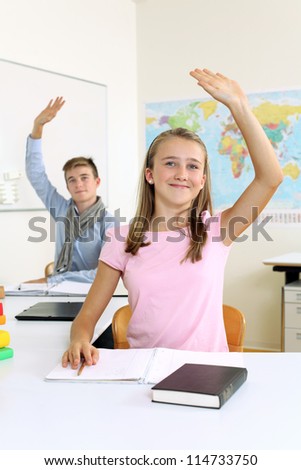 Photo of two students in their class raising their hands to answer a question.