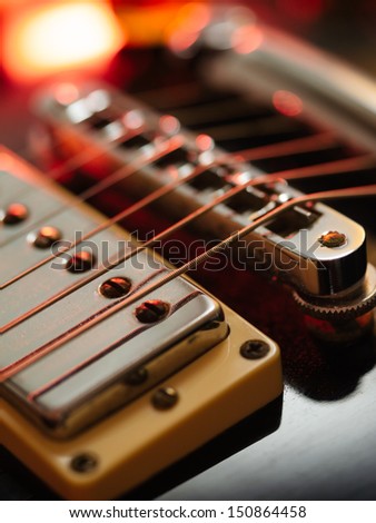 Macro abstract photo of the pickups, bridge and strings of an electric guitar. Shallow depth of field with focus on the first string.