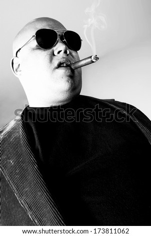 Black and white photo of a cigar smoking gangster.  Harsh lighting for more disturbing look.