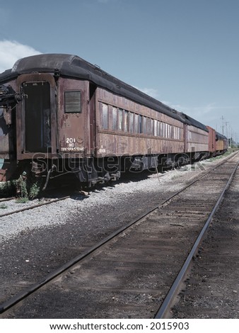 An old passenger train rotting away in a rail yard.