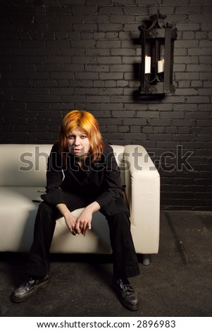 Orange-haired attitude girl sitting alone on a couch.
