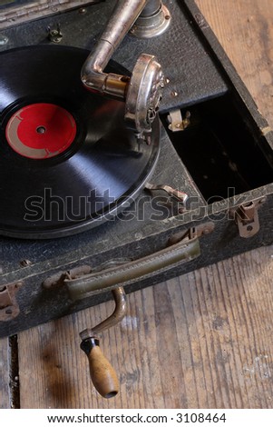 An antique box record player with crank, sitting on the attic floor.