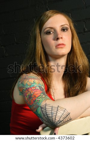 stock photo : A young female with serious stare and arm tattoo.