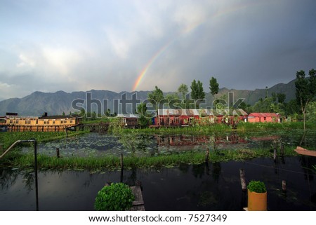 Houseboats in Srinigar, Kashmir (India) - after a light rain a rainbow appears in the distance with mountains as the backdrop.