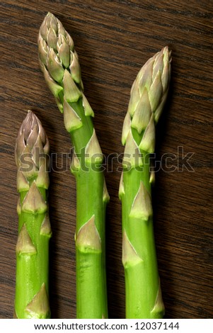Three asparagus tips on a wooden table.