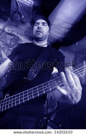 Bass player of a heavy rock band. Shot with strobes and slow shutter speed to create lighting atmosphere, movement, and blur effects.