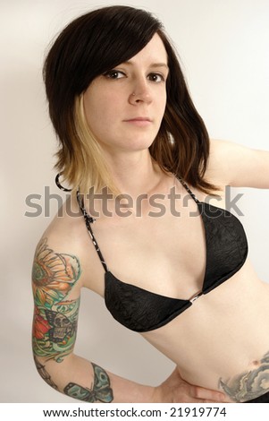 stock photo : Cute young female looking into the camera with arm tattoos and 