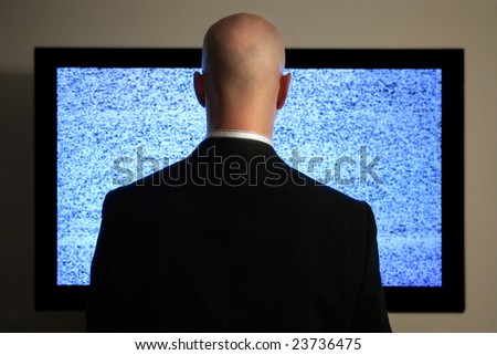 A man watching a blank or static screen of his television.