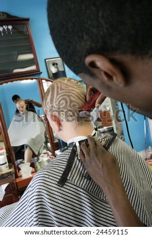 Barber cutting a pattern into a man's hair Three model releases attached Third release is for the framed photo Property is a barbershop and tattoo studio release attached Barber cutting a pattern into a man's hair Three model releases attached Third release is for the framed photo Property is a barbershop and tattoo studio release attached