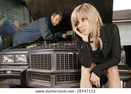 A frustrated blond woman in her thirties waits for a mechanic to fix her old car.