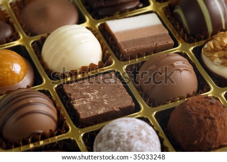 A small assortment of chocolate truffles and pralines in a box.  Very Shallow depth of field, focusing across the middle.