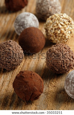 An assortment of chocolate truffles on old wood table.  Very Shallow depth of field, focusing on middle truffle.