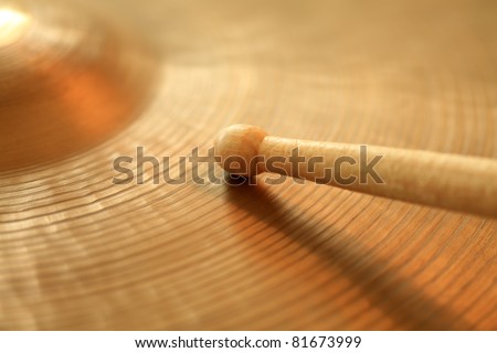 Photo of a drumstick playing on a hi-hat or ride cymbal.  Focus on tip of stick.