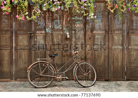 old style rusty brown bicycle and wood door
