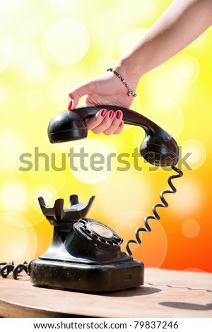 woman hand hanging up the handset of an old black telephone