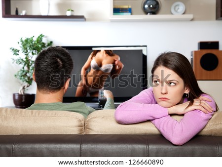 Image of woman getting bored, while her partner watching TV I am the author of image on TV screen