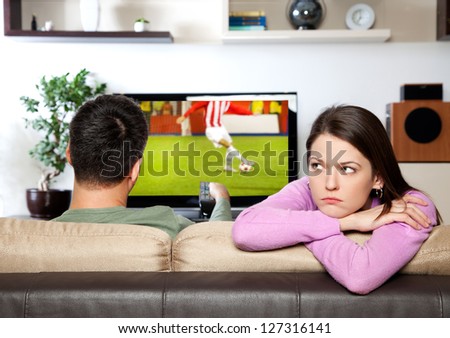 Image of woman getting bored, while her partner watching sports I am the author of image on TV screen