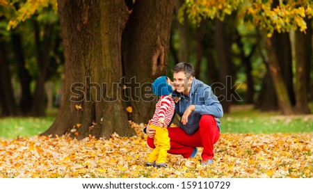 Father and son outdoors, kissing, dressed in colorful clothes. Autumn.