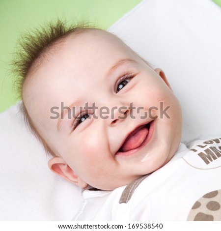 Close up of adorable 6 months old baby laughing and sticking out its tongue