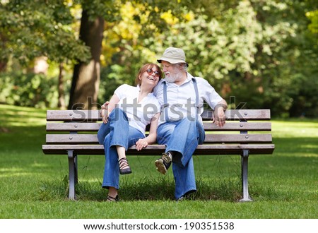 Senior couple sitting on a park bench hugged, shallow depth of field