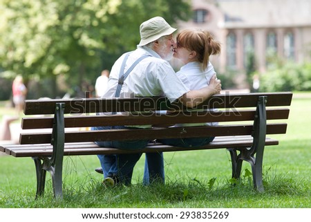 Senior couple kissing on a park bench hugged, shallow depth of field
