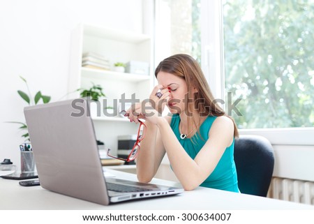 Image of a woman at the office desk, having headache