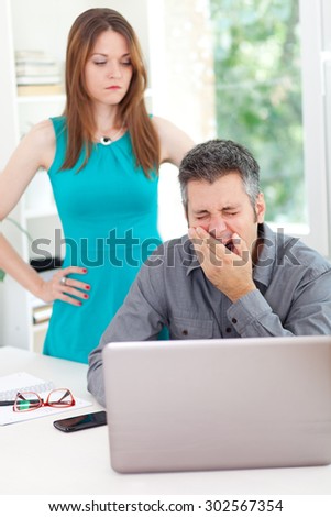 Bossy woman standing over sleepy employee in the office