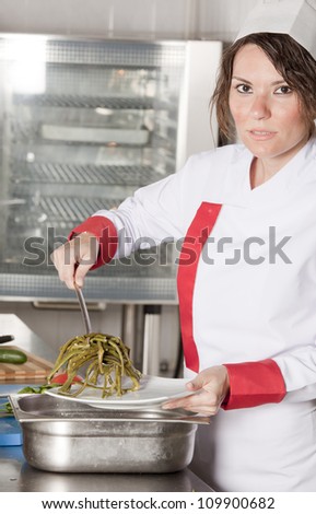 portrait of mid adult female chef in kitchen presenting dish