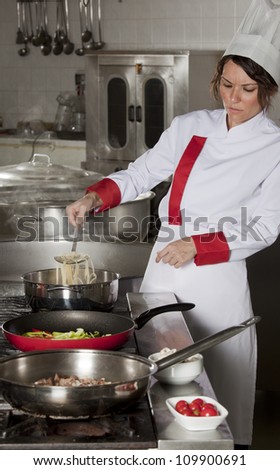 portrait of mid adult female chef in kitchen presenting dish