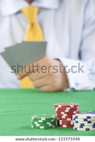 card player with yellow tie  gambling casino chips on green felt background selective focus