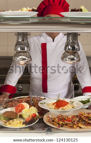 chef standing behind burger and pizza station