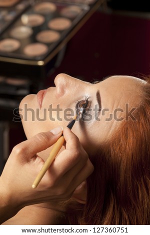 Young beautiful bride applying wedding make-up by make-up artist
