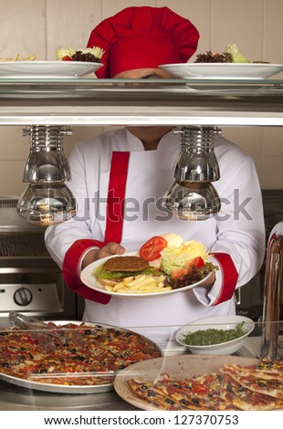 chef standing behind burger,spaghetti and pizza station
