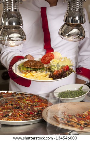 chef standing behind burger,spaghetti and pizza station
