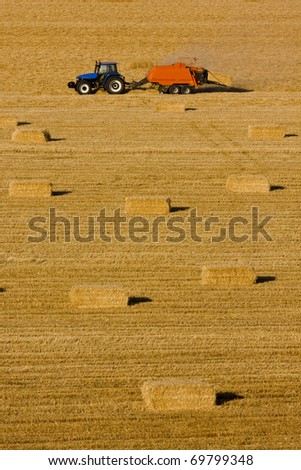 Farmers field full of hay bales with tractor
