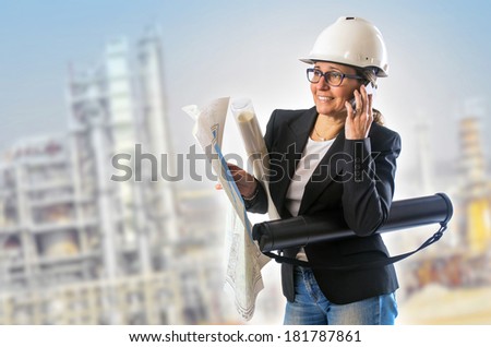 Busy woman engineer with paper and maps and white helmet talking on the phone