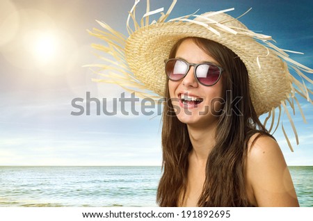 Pretty young girl smiling with straw hat and sun glasses in the beach